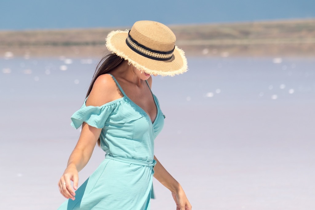 Mein August 2023: Frau mit blauem Kleid und Sonnenhut am Meer